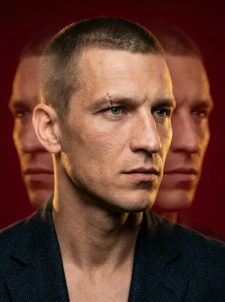 Портрет в тёмном блейзере на красном фоне, по бокам два размытых дубля того же лица