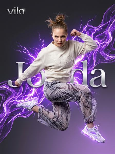Спортивная девушка в прыжке в светлом свитшоте и фиолетовых брюках среди клубов дыма